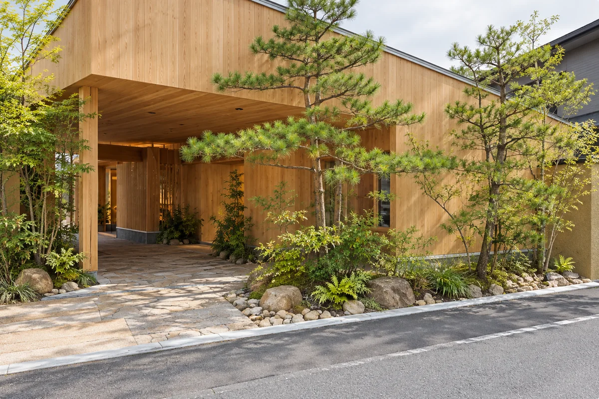 木の外壁と植栽に囲まれた石畳の入口